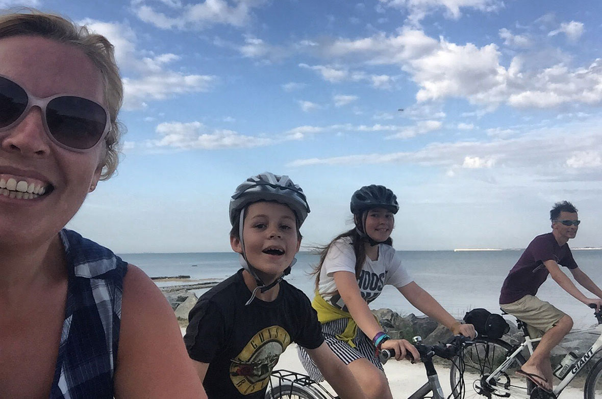 A family of four smiling and riding bikes